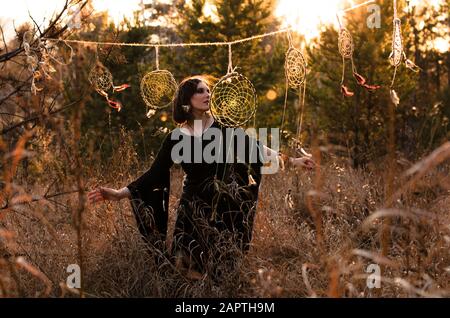 Donna boho con capelli ventosi corti. Silhouette femminile con catcher da sogno attraverso i raggi del sole Foto Stock