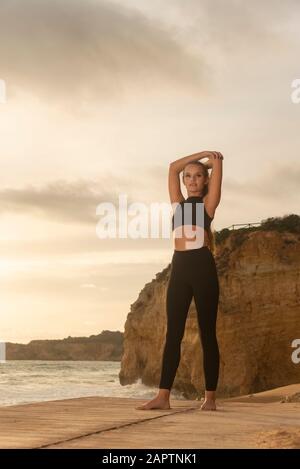 Donna che indossa abbigliamento sportivo stretching, esercizi di riscaldamento sulla spiaggia. Foto Stock