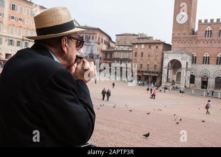 Siena, 27 ottobre 2008: Un uomo illumina un sigaro in Piazza del campo a Siena. Foto Stock