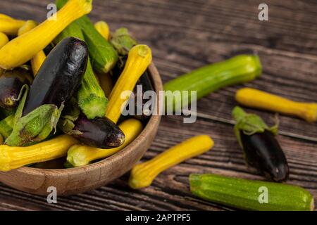 Baby Eggplant e zucchine in ciotola di bambù su sfondo di tavolo di legno Foto Stock