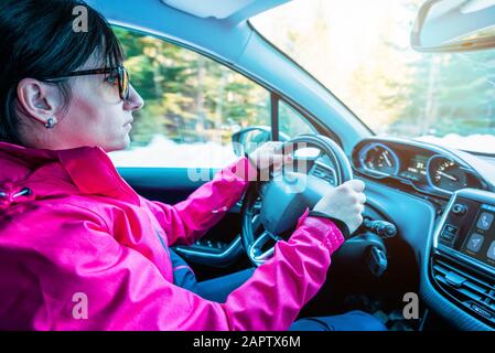 La ragazza nella giacca guida l'auto. Interni moderni. Concetto di sicurezza durante la guida invernale Foto Stock