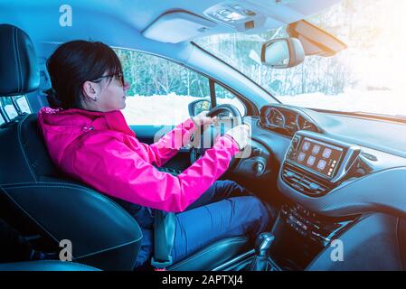 La ragazza guida una moderna vettura SUV. Il concetto di una vacanza invernale in montagna. Interni moderni per auto con display sul cruscotto Foto Stock