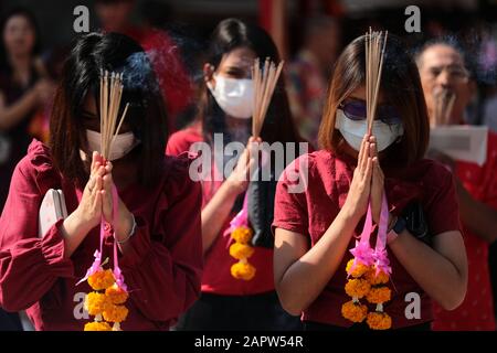 Le donne pregano indossando maschere antipolvere durante la celebrazione al Tempio di Leng Noei Yi a Chinatown, Bangkok. Il nuovo anno lunare, conosciuto anche come Festival di Primavera in Cina, segna l'inizio dell'anno del Rat. La famiglia etnica cinese-tailandese pregano per la buona fortuna e indossano maschere per la protezione dalle polveri mentre il paese lotta per contenere il peggioramento dell'inquinamento atmosferico. Foto Stock