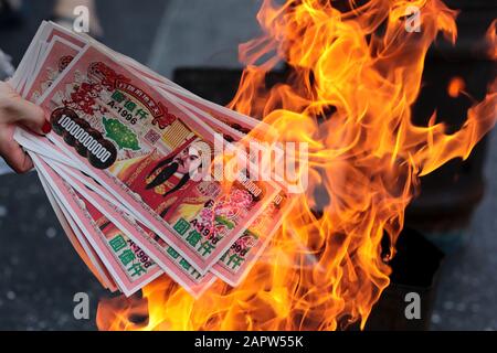 Una donna brucia soldi finti durante la celebrazione a Chinatown, Bangkok.The Lunar New Year, conosciuto anche come Festival di primavera in Cina segna l'inizio dell'anno del Rat. La famiglia etnica cinese-tailandese pregano per la buona fortuna e indossano maschere per la protezione dalle polveri mentre il paese lotta per contenere il peggioramento dell'inquinamento atmosferico. Foto Stock