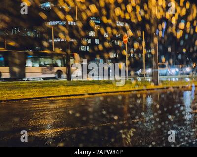 Defocused strada piovosa visto attraverso il parabrezza auto con autobus pubblico guida veloce Foto Stock