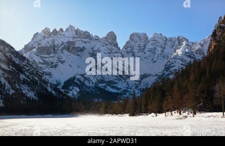 Il Lago Landro nelle dolomiti italiane è completamente ricoperto di ghiaccio con il Monte Cristallo innevato sullo sfondo in una mattinata invernale Foto Stock