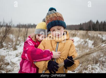 fratelli coccolano mentre giocano fuori sulla neve Foto Stock