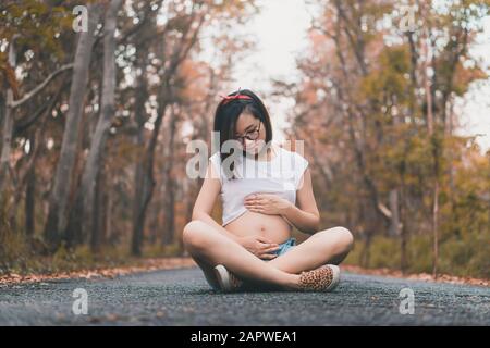 28 anni di madre asiatica per essere delicatamente toccare il suo ventre Foto Stock