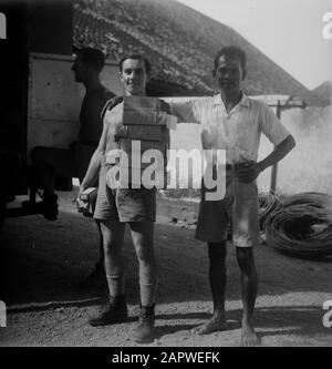 Cucina anteriore e auto mensa (art. P.B.) l'uomo con una pila di pacchetti pone con un uomo indonesiano Data: 1947/04/01 luogo: Indonesia, Indie orientali olandesi Foto Stock