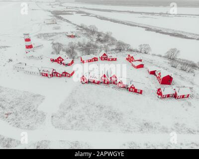 Vista panoramica dei colorati edifici in legno con vista dall'alto. Villaggio di pescatori e città turistica. Case rosse di legno del villaggio di pescatori in nevoso coperto in inverno. Foto Stock