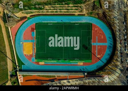 Veduta aerea dall'alto verso il basso di un complesso sportivo multi-funzionale con pista e campo blu, campo da calcio verde e stand in Almansa Spagna Foto Stock