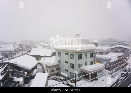 I tetti degli edifici intorno a Yuzawa, Niigata, Giappone, sono coperti in circa 1 metro di neve fresca in una torbida giornata invernale. Foto Stock