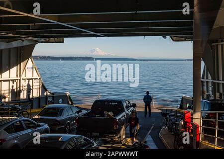 Un uomo si trova sul ponte di un traghetto dello Stato di Washington che guarda fuori il paesaggio. Foto Stock
