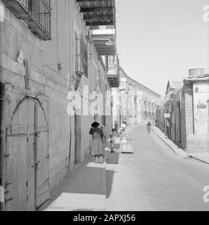 Israele 1964-1965: Gerusalemme (Gerusalemme), Via Mea Shearim nel distretto di Mea Shearim, in essa attività quotidiana Annotazione: MEA Shearim, chiamato anche Meah Shearim o un centinaio di porte, è uno dei quartieri più antichi di Gerusalemme. Fu costruito a partire dal 1870 da ebrei asiatici che vivevano nella Città Vecchia fino ad allora. Tuttavia, c'era troppo poco spazio e così comprarono un pezzo di terra a nord-ovest della città. Questa terra, un'area paludata, fu coltivata in terra per costruire un nuovo quartiere: Meah Shearim. Il distretto è noto anno 2012 come il più estremo quartiere ebraico ortodosso del mondo ed è h. Foto Stock