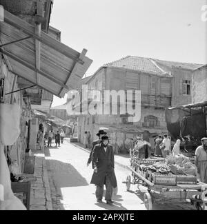 Israele 1964-1965: Gerusalemme (Gerusalemme), Mea Shearim fornitore di strada con cavallo e carrozza e passanti Annotazione: MEA Shearim, chiamato anche Meah Shearim o un centinaio di porte, è uno dei quartieri più antichi di Gerusalemme. Fu costruito a partire dal 1870 da ebrei asiatici che vivevano nella Città Vecchia fino ad allora. Tuttavia, c'era troppo poco spazio e così comprarono un pezzo di terra a nord-ovest della città. Questa terra, un'area paludata, fu coltivata in terra per costruire un nuovo quartiere: Meah Shearim. Il distretto è noto anno 2012 come il quartiere ebraico ortodosso più estremo del mondo ed è sede di Foto Stock