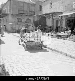 Israele 1964-1965: Gerusalemme (Gerusalemme), Mea Shearim fornitore di strada con cavallo e carrello caricato con scatole piene di bottiglie da bere Annotazione: MEA Shearim, anche chiamato Meah Shearim o cento porte, è uno dei quartieri più antichi di Gerusalemme. Fu costruito a partire dal 1870 da ebrei asiatici che vivevano nella Città Vecchia fino ad allora. Tuttavia, c'era troppo poco spazio e così comprarono un pezzo di terra a nord-ovest della città. Questa terra, un'area paludata, fu coltivata in terra per costruire un nuovo quartiere: Meah Shearim. Il distretto è noto anno 2012 come il quartiere ebraico ortodosso più estremo in t Foto Stock