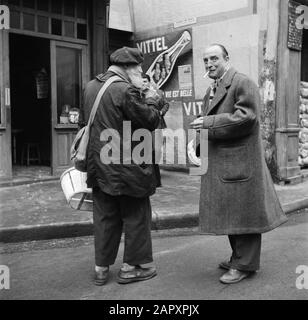 Reportage Parigi Due fumatori uomini in conversazione, sulla strada di fronte al caffè Data: 1950 luogo: Francia, Parigi Parole Chiave: Caffè, headgear, uomini, pubblicità, fumo, immagini di strada Foto Stock