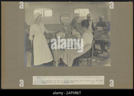 In questo reparto della Twentsche Banketfabriek di Enschede, la torta e la pasta sono pesati e le etichette sono incollate alle scatole di stagno. La produzione è di circa 240 scatole al giorno Data: CA. 1919 Foto Stock