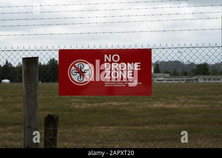 Whenuapai, Auckland, Nuova Zelanda, Nessuna zona del drago nessun segnale di avvertimento rosso e nero volante su chainlink e recinzione a filo spinato intorno ad un aeroporto. Foto Stock