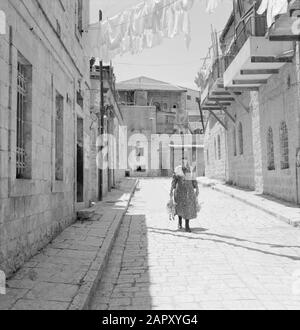 Israele 1964-1965: Gerusalemme (Gerusalemme), Mea Shearim Donna camminare lungo la strada con pollame in entrambe le mani Annotazione: MEA Shearim, anche chiamato Meah Shearim o un centinaio di porte, è uno dei quartieri più antichi di Gerusalemme. Fu costruito a partire dal 1870 da ebrei asiatici che vivevano nella Città Vecchia fino ad allora. Tuttavia, c'era troppo poco spazio e così comprarono un pezzo di terra a nord-ovest della città. Questa terra, un'area paludata, fu coltivata in terra per costruire un nuovo quartiere: Meah Shearim. Il distretto è noto anno 2012 come il quartiere ebraico ortodosso più estremo del mondo ed è hom Foto Stock