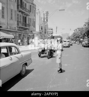 Israele 1964-1965: Tel Aviv, poliziotti sulla strada controllore del traffico femminile al centro della strada (Allenby Road/ Carmel Market) Data: 1964 Località: Israele, Tel Aviv Parole Chiave: Vita quotidiana, flauti, moto con sidecar, ombra di goccia, traffico cittadino, immagini di strada, uniformi, controllori di traffico, pedoni, negozi Foto Stock