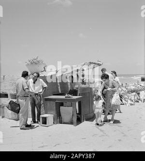 Israele 1964-1965: Tel Aviv, il Sabbath al mare la gente vestito Summerly mangia melone sul bordo della spiaggia ad una semplice stalla Annotazione: Durante il Sabbath molte persone da Tel Aviv al mare Data: 1964 luogo: Israele, Tel Aviv Parole Chiave: Bagnanti, vita quotidiana, frutta, conversazioni, bancarelle, spiagge Foto Stock