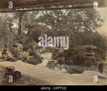 Vista sul giardino dalla veranda di una casa da tè giapponese. C'è un cane che dorme sul portico. Nelle palme da giardino o nelle felci di alberi, una statua del giardino di una gru e una lanterna da giardino. Giappone, luogo sconosciuto [forse dintorni di Nagasaki], non ondato [Foto appartenenti ad una serie di 42 stampe nella collezione di Savings City Photo di Felice Beato, Kusakabe Kimbei o Baron Raimmund von Stillfried]. Sulla base di Claudia Gabriele Philipp, Dietmar Siegert, Rainer Wick (ed), Felice Beato in Giappone; Photographien zum Ende der Feudalzeit 1863 1873, Heidelberg/M 1991, pagina 98, questa immagine è attribuibile a Fel Foto Stock