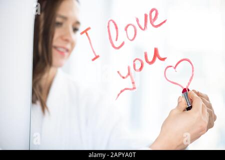 Mano di giovane amorosa donna che scrive amore messaggio e che disegna piccolo cuore Foto Stock