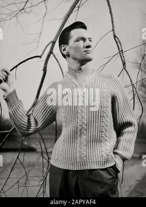 Moda casalinga, moda maschile, maglieria. Uomo in maglia con collo a V con maniche raglan a coste con cavi. Paesi Bassi [1960-1969]. Foto Stock