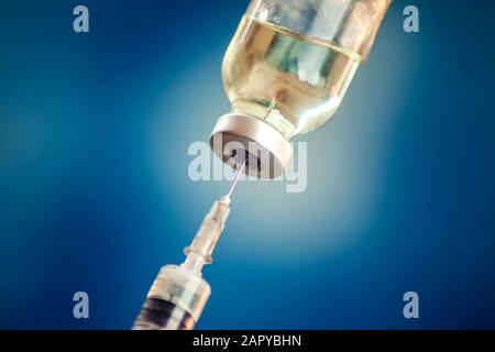 Un flacone con vaccino e siringa davanti a fondo blu. Primo piano. Medicina, scienza e concetto di assistenza sanitaria Foto Stock