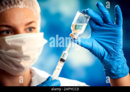 Un medico in guanti medici che tiene un flacone con vaccino e siringa prima di effettuare l'iniezione. Primo piano. Medicina e concetto di assistenza sanitaria Foto Stock