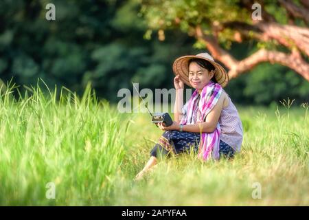 Donna che tiene radio in campo di riso Foto Stock