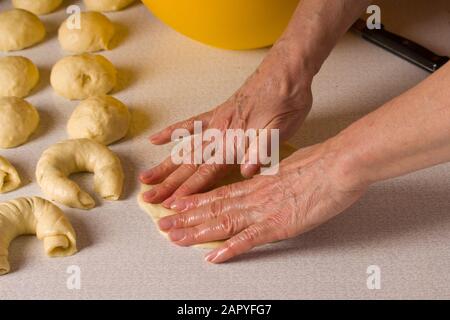 le mani delle donne rotolano l'impasto su un bagel. Foto Stock