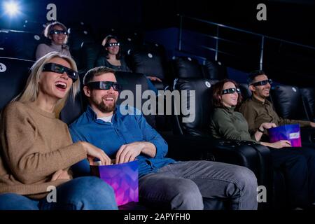 Giovane uomo e donna ridenti e i loro amici in 3d occhiali guardare film Foto Stock