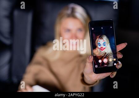 Mano di giovane donna bionda con applicazione multimediale con filtro maschera viso Foto Stock