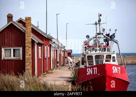 Case di pescatori rossi / cabine rorbuer e barche da pesca nel piccolo porto di Graesgard / Gräsgård, Öland, Svezia Foto Stock