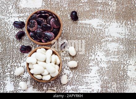 Diversi tipi di legumi - fagioli cannellini, nero e fagioli rossi, Lima e Fagioli Pinto aveva ordinato in ciotole di legno. Foto Stock