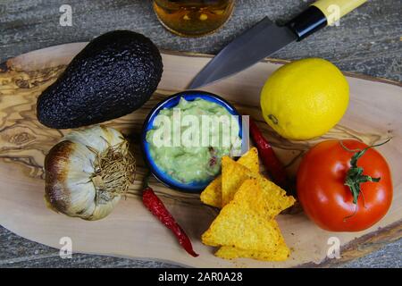 Ingredienti per guacamole: Avocado, agrumi, pomodoro, aglio, peperoncino, coltello, tacos su tavola di legno Foto Stock