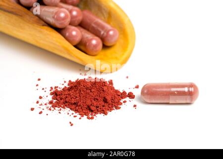 Riso di lievito rosso o angkak o polvere di riso kojic e capsula supplementare su sfondo bianco isolato Foto Stock