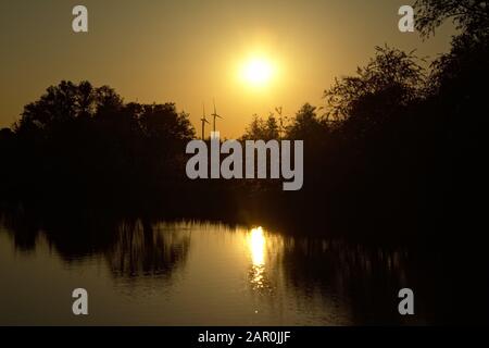 Il tramonto si riflette nell'acqua del canale `de moer` e le sagome di alberi e mulini a vento sulle argine Foto Stock