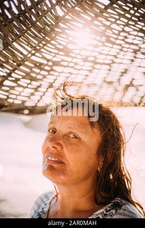 Donna Caucasica Adulta Si Rilassò Posando Sotto Spiaggia Umbrella Al Tramonto. Vacanza Sul Mare Oceano. Foto Stock