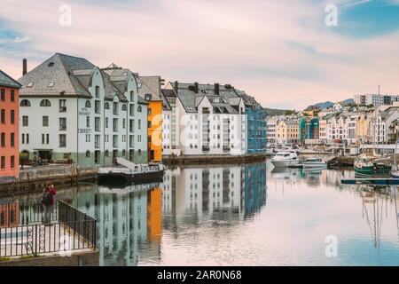 Alesund, Norvegia - 19 Giugno 2019: Giovane Donna Turista Fotografo Di Turismo Scattare Foto Di Vecchie Case Di Legno In Nuvoloso Giorno Estivo. Arte Nouve Foto Stock