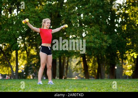 Una giovane donna entra per lo sport all'aperto. Ragazza con capelli biondi sta allenando nel parco sulla natura. Foto Stock