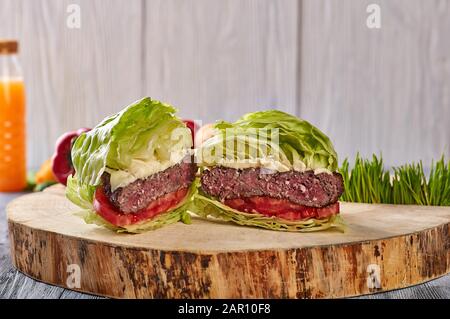 hamburger di manzo medio arrosto con insalata, senza panini su fondo di legno, accompagnato da verdure fresche e succo Foto Stock