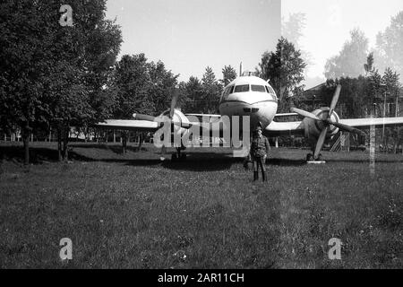 Stupino, REGIONE DI MOSCA, RUSSIA - CIRCA 1992: Un soldato dell'esercito russo sullo sfondo di un aereo di trasporto Ilyushin il-14. Bianco e nero. Scansione su pellicola. Grano grande. Difetto di esposizione multipla. Foto Stock