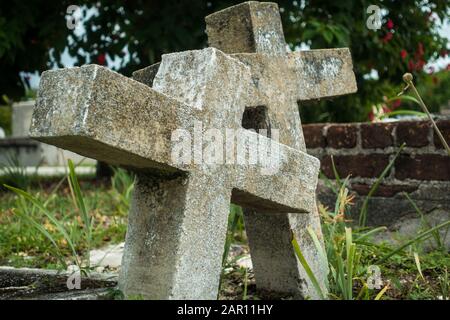 Coppia di vecchi lapidi nel cimitero cristiano poggiati insieme come simbolo dell'amore eterno. Closeup di pietre stagne, luce del giorno, nessuna gente Foto Stock