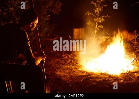 uomo seduto bruciare legno di eucalipto in un campo intenso fuoco los pellines cile Foto Stock