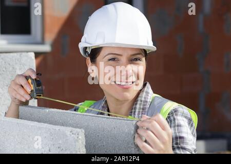 giovane e attraente architetto o ingegnere femminile che tiene il nastro di misurazione Foto Stock