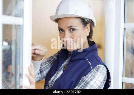 un costruttore femmina che fissa la finestra Foto Stock