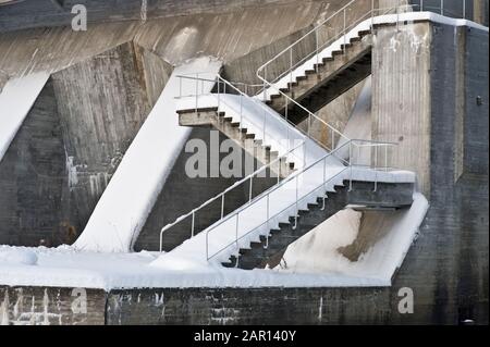 Diga in cemento con scala coperta di neve. Foto Stock